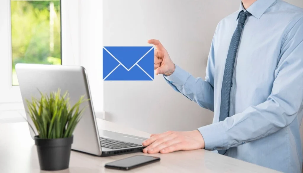 Email Marketing for Cannabis Brands 34 Business professional holding blue email icon while working on laptop for automated cannabis marketing