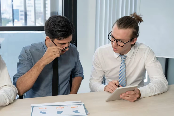 Two men discussing over a tablet.